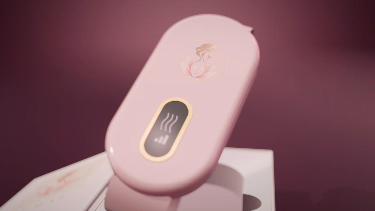 La ceinture chauffante Lumae rose poudré, son écran allumé, au-dessus de son coffret.