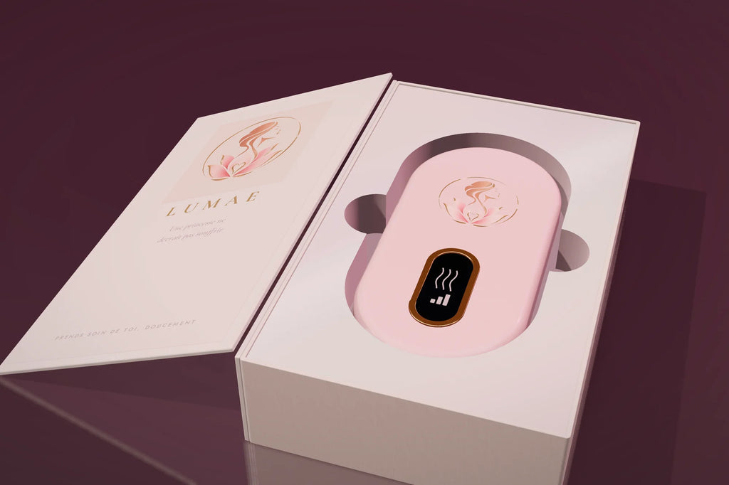 Le coffret Lumae ouvert comme un livre, la ceinture chauffante rose poudré dans son écrin nacré.