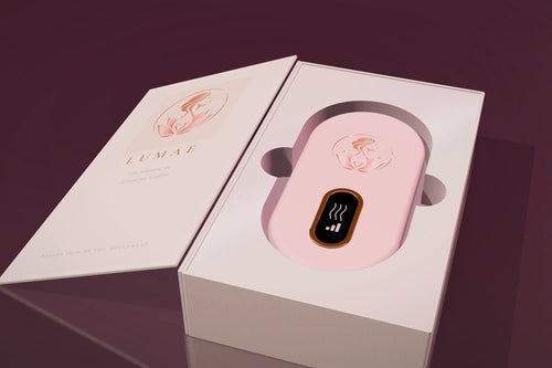 Le coffret Lumae ouvert comme un livre, la ceinture chauffante rose poudré dans son écrin nacré.