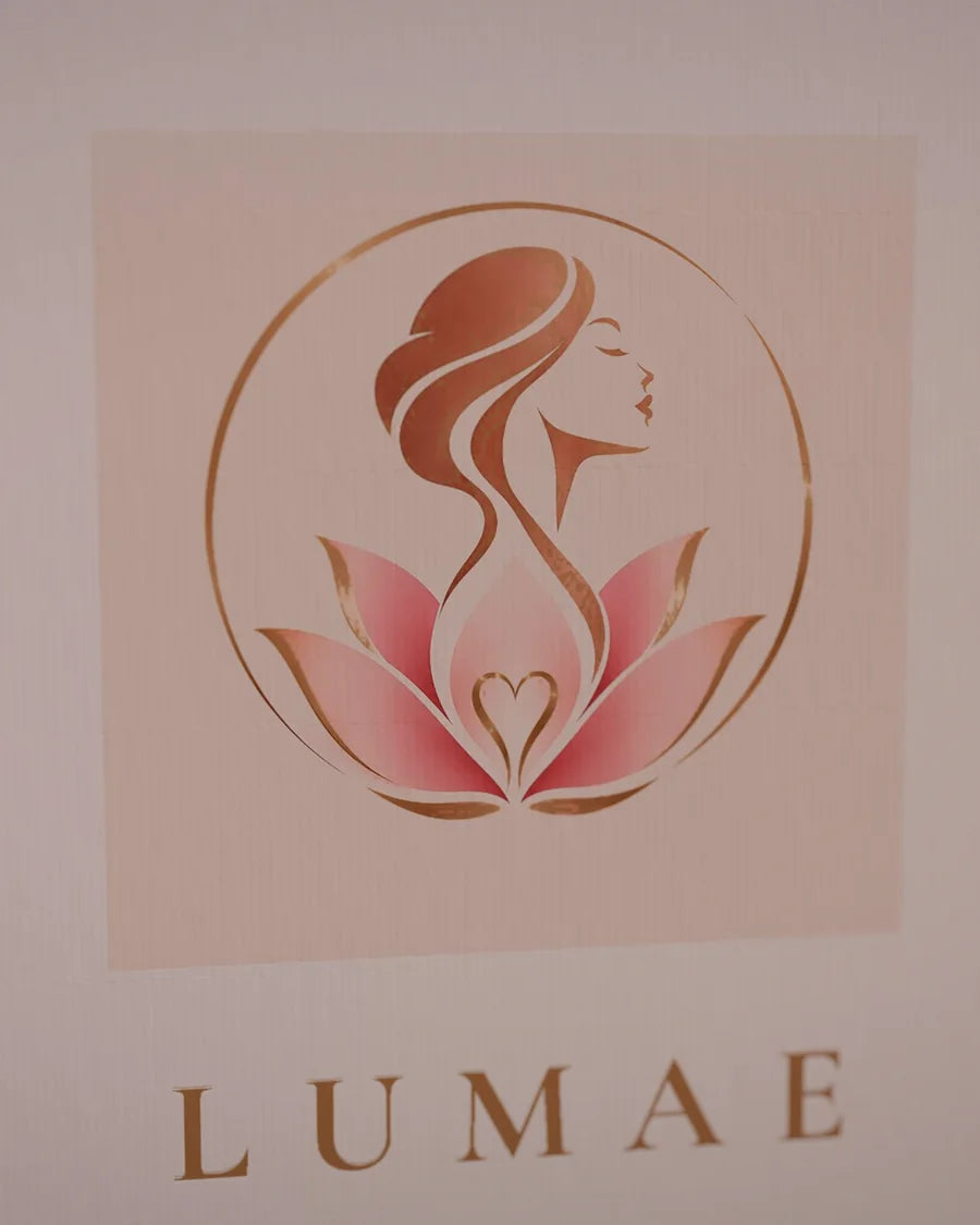 Détail de la couverture du coffret : le logo Lumae doré sur papier rose poudré.